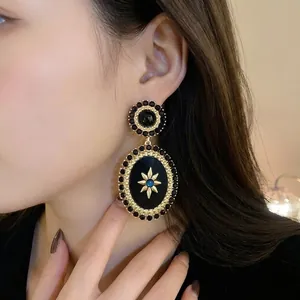 Elegant vintage court style oval gold earrings with black enamel and starburst motif