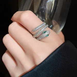 Detail shot of a sparkling silver snake wrap ring featuring green marquise eyes.