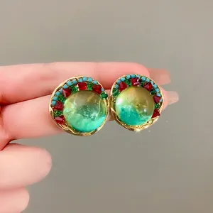 Vintage palace style round earrings featuring a green translucent orb and red crystals