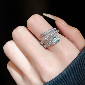 Detail showing the sparkling zircon-paved snake head and green eyes on a silver ring