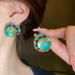 Close-up detail of vintage green round earrings with colorful crystal accents on the ear.
