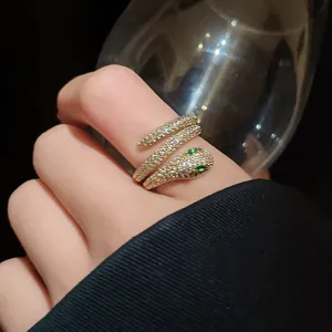 Detailed close-up of a sparkling pavé snake wrap ring featuring vibrant green eyes