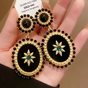 Detailed macro view of vintage palace style oval drop earrings with starburst motif
