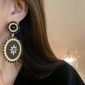 Detailed close-up of vintage palace style oval dangling earrings with a black gold starburst.