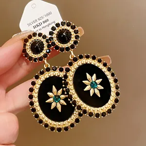 Vintage oval dangle earrings featuring black enamel, gold starburst, and rhinestones.