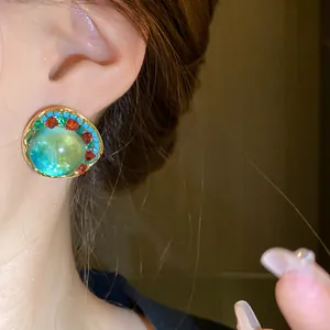 Detailed macro view of a vintage green round stud earring with colorful rhinestones