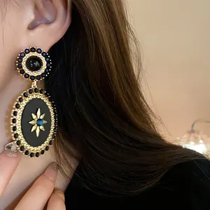Close-up of vintage palace style oval drop earring with black and blue accents