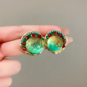 Detailed view of vintage green round earrings with red and green rhinestones and gold finish