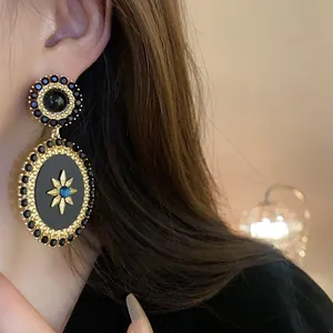 Close-up of vintage palace style oval earrings with black enamel and starburst