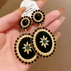 Macro view of vintage royal style gold dangle earrings with black and green stones.