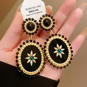 Close-up of vintage court style oval drop earrings with black crystals and sunburst