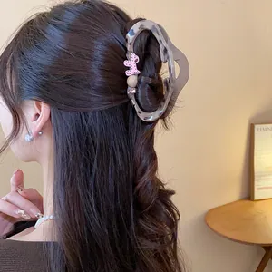 Close-up detail of leopard print hair claw clip with a pink puppy ornament in hair