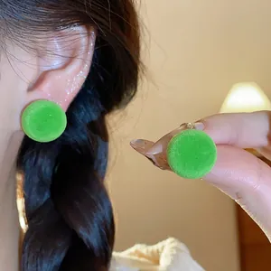 Detalle de pendientes redondos de flocado verde con textura invernal acogedora