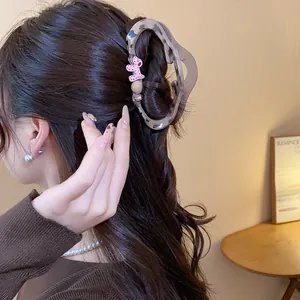 Close-up of a stylish leopard print hair claw clip with a pink dog charm on a model's hair.