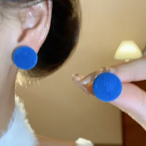 Primer plano de pendientes redondos aterciopelados azules con textura suave y vibrante