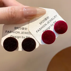 Detalle de pendientes redondos de flocado con agujas de plata S925 en rojo y marrón