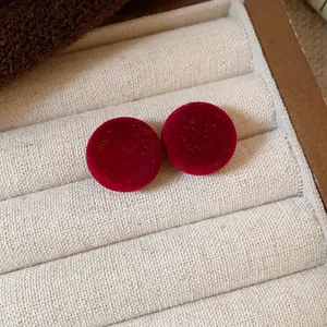 Detalle de los elegantes pendientes redondos flocados rojos en una bandeja de joyas