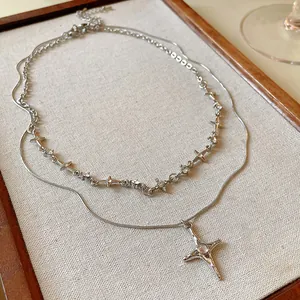 Dettaglio di un'elegante collana doppia in argento con stelle e ciondolo a forma di croce