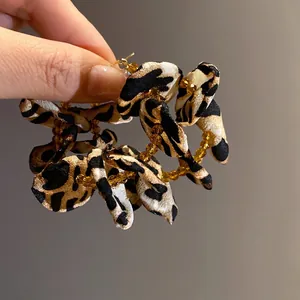 Large fabric leopard print hoop earrings with amber beads and floral-inspired texture design