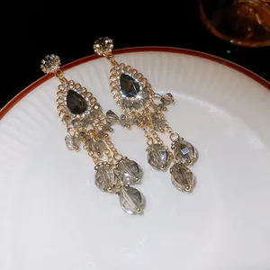 Elegant long grey crystal tassel earrings with silver needle on a porcelain plate.
