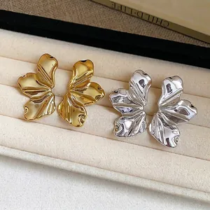 Elegantes pendientes de botón con forma de hoja texturizada en oro y plata en bandeja