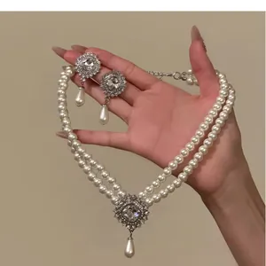 Elegant double-strand pearl necklace and teardrop earring set with crystal pendant detail