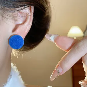 Primer plano de pendientes redondos flocados azules con textura de terciopelo suave