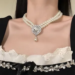Elegant double-strand pearl necklace with vintage crystal pendant and teardrop pearl detail.