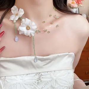 Dettaglio della collana con fiori in tessuto, perline verdi e gocce di vetro blu