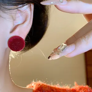 Detalle de pendientes redondos de flocado rojo puestos en la oreja para estilo invernal