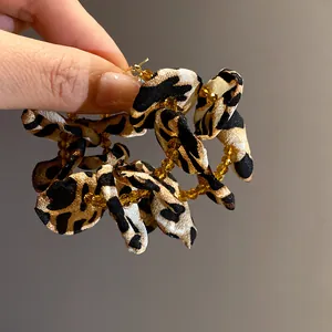 Detailed view of leopard print fabric flower hoop earrings with amber beads