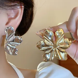 Vista macro de pendientes de hoja de metal texturizado en plata y oro para moda femenina