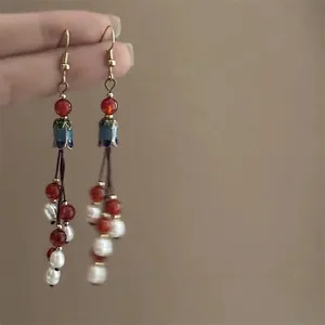 Detail view of Bohemian tassel earrings with red beads and oil-dripped flower charms