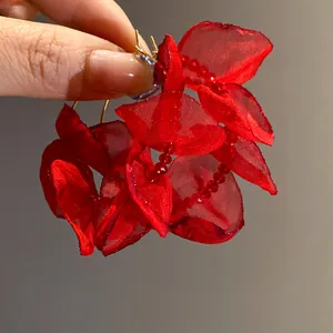 Close-up detail of red fabric flower hoop earrings with beaded accents