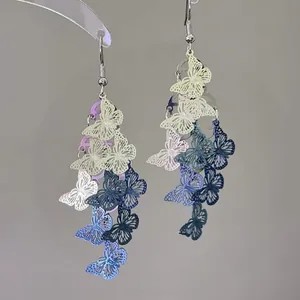 Close-up of spray-painted hollow butterfly dangle earrings in blue and yellow colors