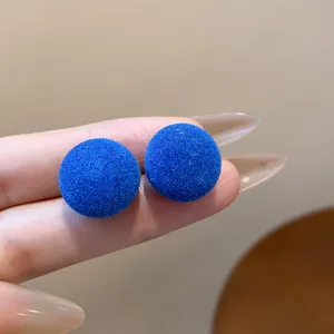 Primer plano de pendientes redondos de flocado azul brillante con textura aterciopelada
