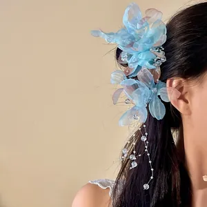 Detail view of a blue mesh flower hair clip with delicate pearl tassels.
