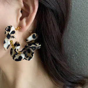 Close-up of stylish leopard print fabric hoop earrings with golden bead accents.