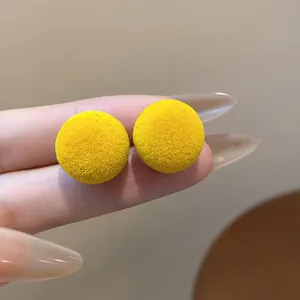 Primer plano de pendientes de bola flocada de color amarillo con textura de terciopelo