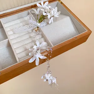 Macro detail showing white gauze flower hair clip with elegant pearl tassels and lace