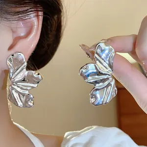 Detalle de pendientes con forma de hoja de metal texturizado en acabado plateado