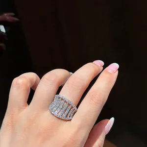 Macro view of a sparkling hollow-out zircon wide ring worn on a woman's index finger.