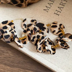 Detailed macro view of leopard print fabric flower hoop earrings with amber beads