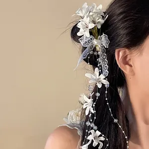 Close-up detail of white fabric floral hair clip with elegant lace tassel and beads