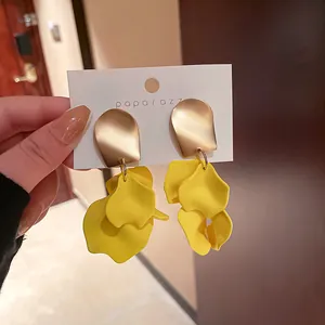 Dettaglio di orecchini oversize a petalo di rosa gialla con eleganti borchie in oro opaco