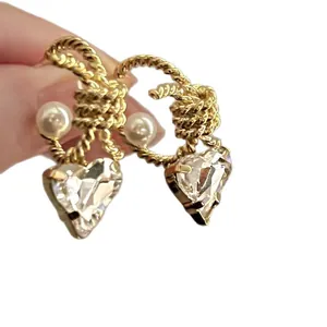 Stylish C-shaped twisted rope earrings with pearl and heart-shaped crystal charms.
