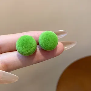 Vista macro que muestra la suave textura flocada verde de los pendientes redondos.