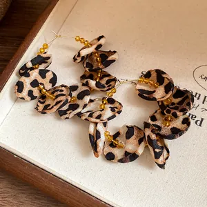 Detailed close-up of leopard print fabric petals and amber beads on hoop earrings