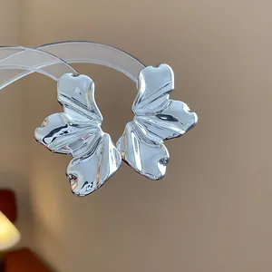 Primer plano de pendientes de hoja plateados con textura ondulada y acabado brillante