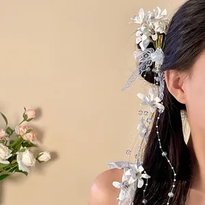 Elegant fabric flower hair clip with long lace tassels worn on a side hairstyle